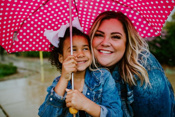 woman in blue denim jacket holding umbrella smiling