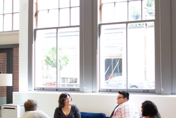 four persons sitting on chairs near window during daytime