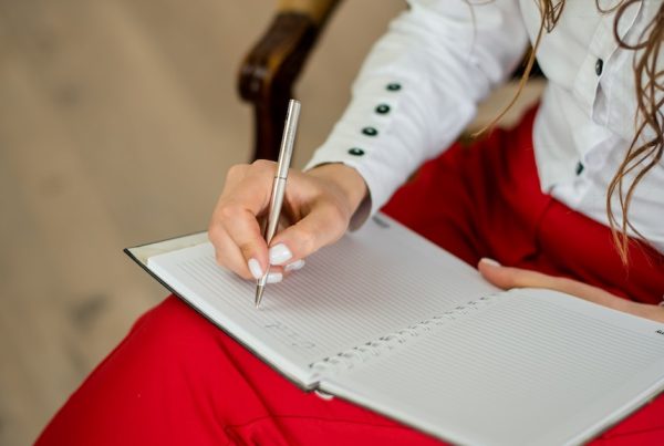 woman in white long sleeve shirt writing on white paper