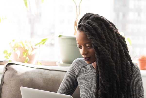 woman sitting on sofa with Macbook on her lap