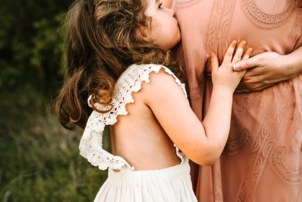 child kissing woman's tummy