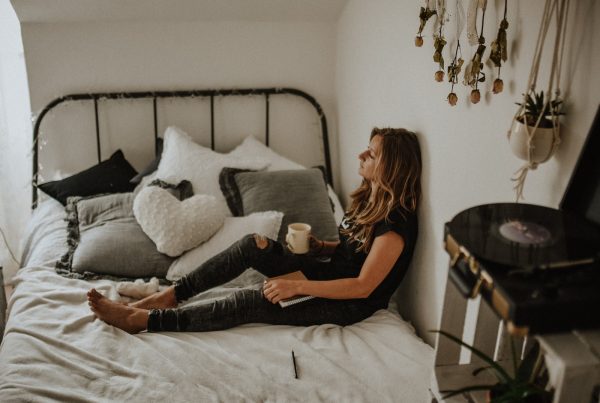 woman leaning on wall while sitting on bed