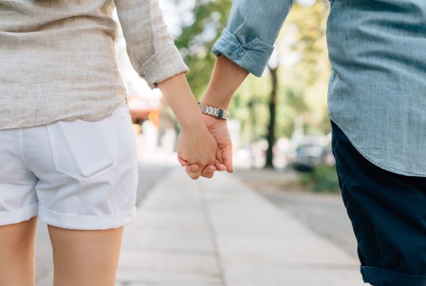 teenage man and woman holding hands together in walkway during daytime